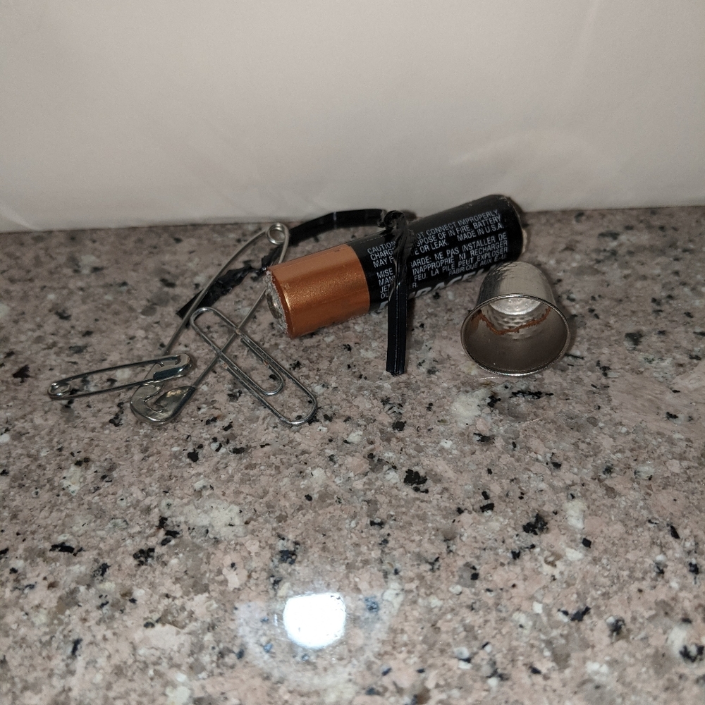 A thimble a battery and others pictured.